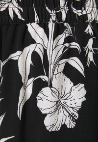 Zwarte stof met witte botanische print met grote hibiscus bloemen en lange bladeren met fijne zwarte details.