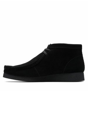 Black suede ankle boot with a rounded toe, lace-up design, and textured black rubber sole. Side stitching detail adds dimension.