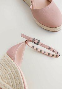 Pink leather espadrille wedges with a woven jute sole. Features a buckle strap with silver studs and a smooth, textured upper.
