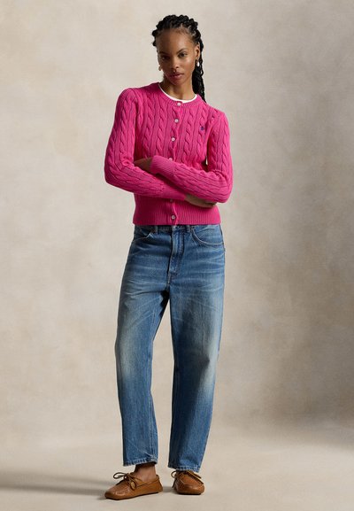 Φουξια ροζ ζακέτα πλεκτή με στρογγυλή λαιμόκοψη, κλείσιμο με κουμπιά, συνδυασμένη με τζιν κανονικής γραμμής ανοιχτού πλυσίματος και καφέ δερμάτινα μοκασίνια.