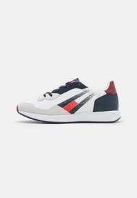 Sneaker con parte superiore in tessuto bianco, dettagli blu navy, cappuccio in suede grigio, design a strisce rosse e blu navy, e suola in gomma bianca testurizzata.