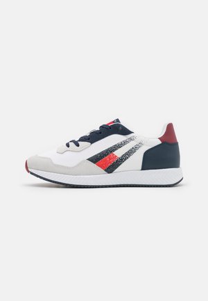 Sneaker con parte superiore in tessuto bianco, dettagli blu navy, cappuccio in suede grigio, design a strisce rosse e blu navy, e suola in gomma bianca testurizzata.