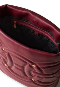 Deep burgundy leather tote bag with a smooth finish, featuring a quilted design, gold-tone hardware, and a black patterned interior lining.