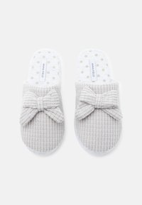 Zapatillas grises con textura y detalle de lazo, que cuentan con una plantilla blanca con lunares y un diseño suave y acolchado para mayor comodidad.