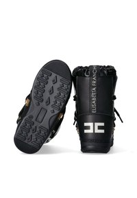 Stivali neri impermeabili con suola in gomma testurizzata, polsino elastico e dettagli in metallo dorato. Presentano un logo sul lato.