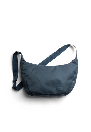 Dark navy shoulder bag made of smooth fabric, featuring a wide shape, adjustable strap, and a small logo patch on the front.