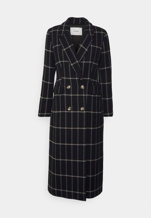 Tumesinine kahekordne pikk jakk, millel on kreemiline ruuduline muster. Omab kuldsetes toonides nööpe ja kahte küljetaskut. Valmistatud kudumiskangast.