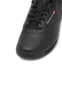 Musthave musternahk nahkkingad tekstureeritud pinnaga, ümar tipuga, perforatsioonide ja mustade lipsudega. Küljel on Reeboki bränding.