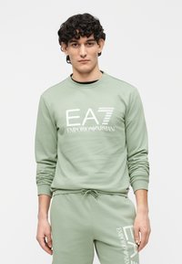 Lichtgroene sweatshirt met lange mouwen en een ronde hals. Heeft een witte EA7 Emporio Armani-logo op de voorkant. Soepele stoftextuur.