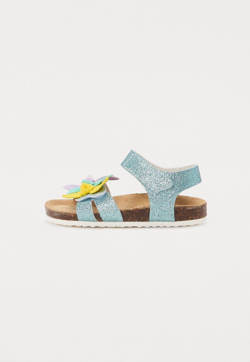 Glittriga turkosa sandaler med en korkfotbädd; har en dekorativ blomma i pastellfärger. Remdesign med öppen bak.