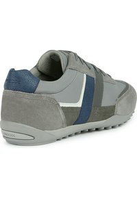 Zapatilla deportiva gris con una combinación de materiales de ante y malla. Cuenta con una franja de acento azul y un talón texturizado, además de una suela de goma.