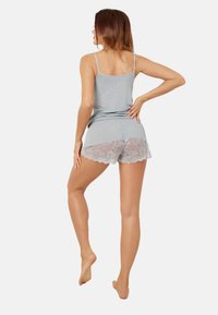 Szary top na ramiączkach i szare szorty z falbanką koronkową. Materiał wydaje się gładki i miękki.