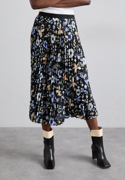 Jupe midi plissée à fleurs avec un fond noir, ornée de fleurs bleues, blanches et oranges. Associée à des bottes noir et crème jusqu'au genou.