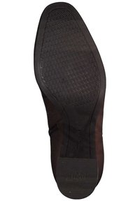 Suela de zapato de goma negra con un patrón de agarre texturizado, puntera redondeada y una zona arqueada lisa, con un sutil logotipo en el talón.
