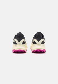 Ett par svarta och beige Salomon terrängskor med rosa texturerade sulor, visade bakifrån på en vit bakgrund.