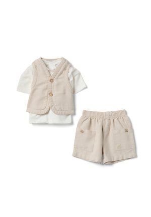 Chaleco beige abotonado sobre una camisa blanca de manga corta, combinado con pantalones cortos beige con cintura elástica y bolsillos delanteros con botones.