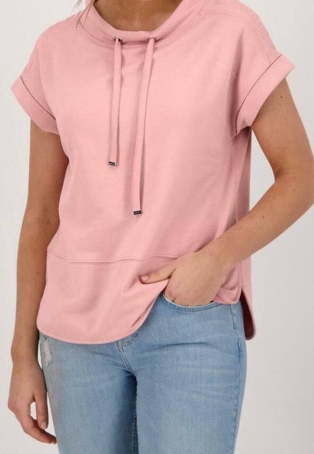 Top corto rosa claro de manga corta con cuello alto, cierre con cordón y corte holgado. Tejido suave con una textura lisa y aberturas laterales.