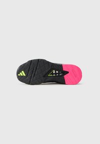 Black athletic shoe sole with a diagonal pink section, textured surface, and triangular accents. Features "TRAXION" and logo details.