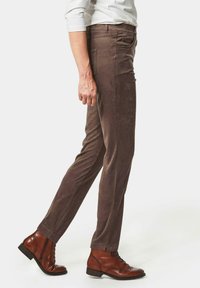 Bruine suède broeken met een slim fit, voorzakken en een subtiele textuur, gecombineerd met bruine leren brogue laarzen.
