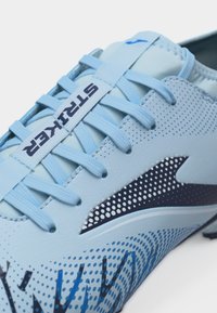 Ανοιχτό μπλε ποδοσφαιρικό παπούτσι με υφασμένες κορδόνια, μαύρο και λευκό λογότυπο με κουκκίδες και ετικέτα "STRIKER" στη γλώσσα, σχεδιασμένο για ποδόσφαιρο.