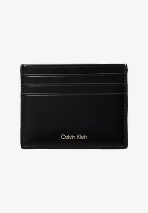 Czarny skórzany etui na karty z trzema przegródkami na karty i srebrnym logo "Calvin Klein" umieszczonym na środku u dołu z przodu.