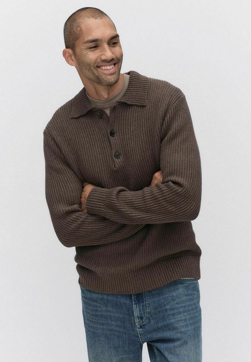 Brun ribbad stickad tröja med krage och tre knappar, tillsammans med ljusblå denimjeans. Texturen ser mjuk och tjock ut.