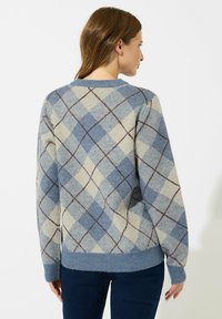 Sweter dzianinowy z jasnoniebieskim, kremowym i brązowym wzorem argyle. Żebrowane mankiety i dół oraz regularny krój. Miękka faktura.