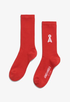 Chaussettes rouges côtelées en tissu, avec un logo blanc sur le côté et le nom de la marque imprimé en blanc au bas.
