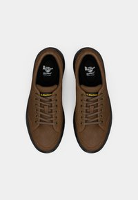 Barna bőr sportcipő kerek orral, fekete gumitalppal, illeszkedő fűzőkkel és sárga logó részletekkel a nyelven. SoftWair párnázással.