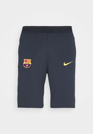 Granatowe krótkie spodenki sportowe z herbem FC Barcelona na lewej nodze i żółtym logo Nike na prawej nodze, z elastyczną talią.