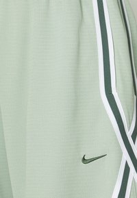 Hele roheline spordikangas väikeste perforatsioonidega, tumeroheline ja valge triibuline äär ning tumeroheline Nike swoosh logo.