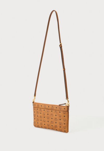 Sac bandoulière en cuir marron avec sangle ajustable et motif de logo noir répété sur la surface.