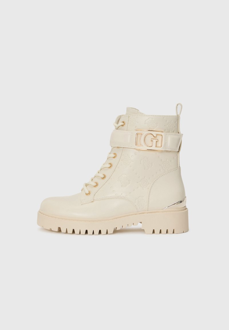 Botas de combate beige con cordones en la parte delantera, correa decorativa con logotipo, patrones florales texturizados y suela robusta con un agarre prominente.