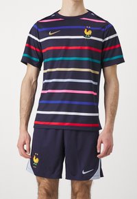 Pánské sportovní oblečení Nike s námořnickým pruhovaným designem v barvách jako červená, růžová a zelená, s emblémem kohouta. V kombinaci s námořnickými šortkami.