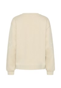 Sweatshirt crème avec des manches longues, des poignets côtelés et une coupe décontractée. Des broderies florales sur chaque manche ajoutent de la texture.