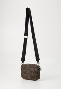Crossbody taske med rektangulært design, brunt stof med et gentagende logo mønster, sort justerbar rem, sølv lynlås og hardware detaljer.