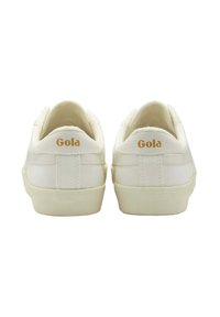 Vita Gola-sneakers med en slät tygöverdel, texturerad baksida och detaljer i guld på hälen. Klassisk låg modell.