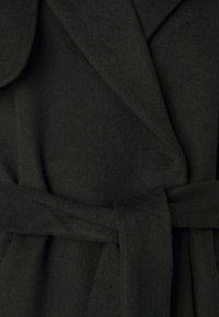 Cappotto in lana nera con una texture morbida, dotato di colletto a scialle, cintura avvolgente e design strutturato.