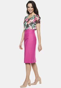Kwiatowa bluzka z krótkimi rękawami, zestawiona z dopasowaną różową spódnicą ołówkową. Spódnica ma rozcięcie z tyłu i ukrytą zamek. Beżowe koturny.