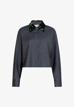 Korte donkere grijze blouse met een zak, voorzien van een zwart kraagje met pailletten in groene en blauwe tinten. Soepele textuur.