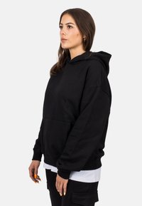 Sudadera con capucha negra hecha de algodón, que cuenta con un bolsillo frontal y puños de canalé. El diseño es de corte relajado y tiene una textura suave.