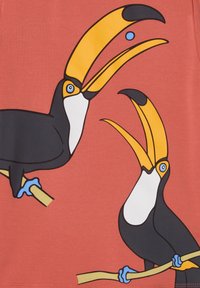 Roter Stoff mit einem grafischen Design, das zwei Tukane mit großen gelben Schnäbeln zeigt, die auf hellbraunen Ästen vor einem Korallenhintergrund sitzen.
