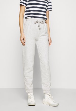 Ljust grå kofreservatbyxor med elastiska mudd och dragsko i midjan, i kombination med en t-shirt i marinblå och vit randig design samt vita sneakers.