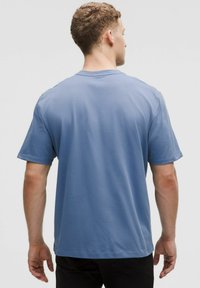 Heledane lühikeste varrukatega T-särk, millel on ümber kaela lõige, valgest pehmest kangast, lõdva lõike ja sirge alläärega.