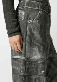 Pantaloni in denim grigio con effetto slavato, dotati di cuciture a contrasto, tasche laterali e vestibilità comoda. Tessuto strutturato con cuciture visibili.