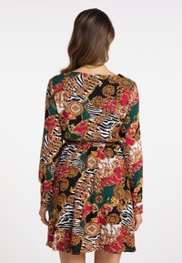 Långärmad klänning i svart med livfulla blommönster och zebramönster, med en figursydd midja och flödande kjol. Tillverkad av lättviktsmaterial.