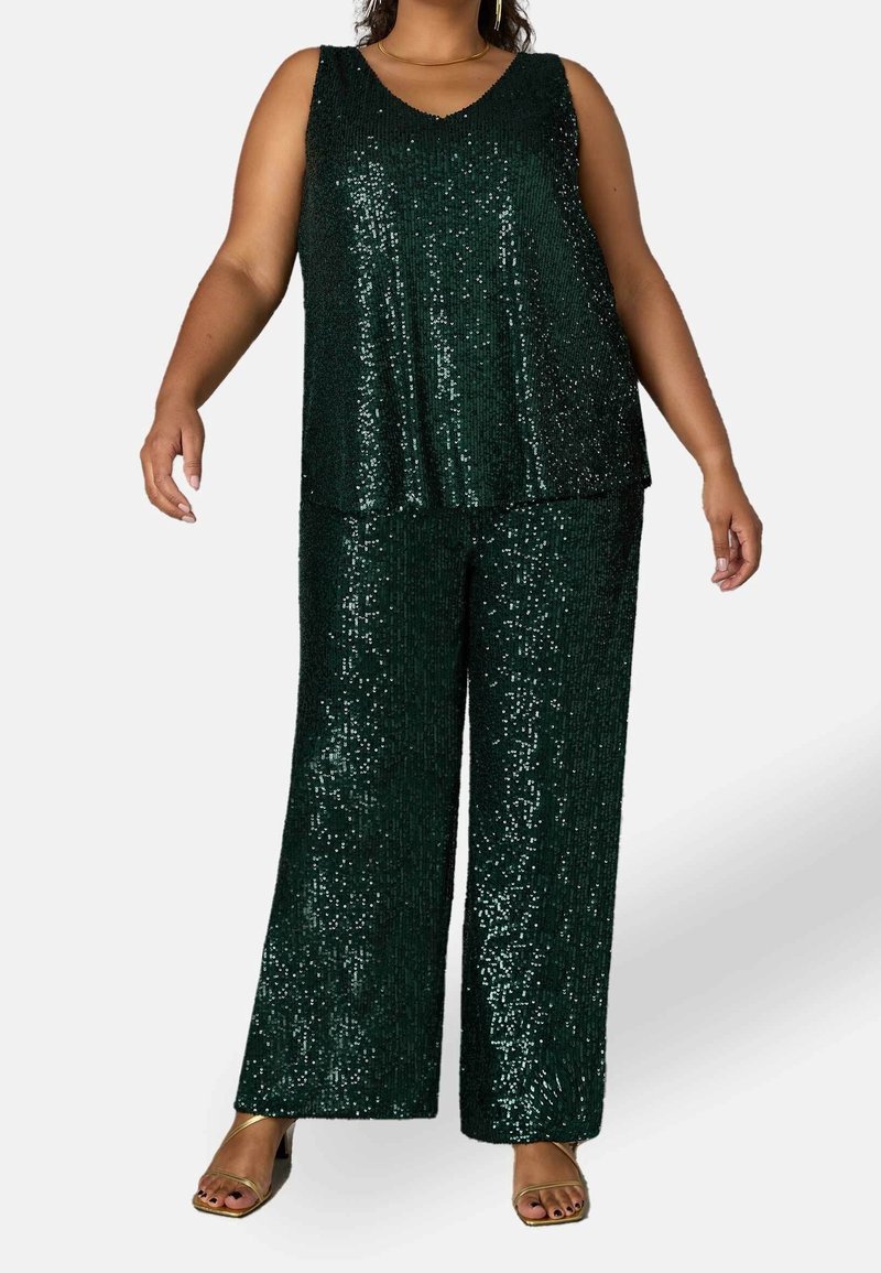 Grön paljettopp med V-hals och lös passform, kombinerad med vida paljettbyxor. Båda plagg har glänsande, reflexiva texturer.