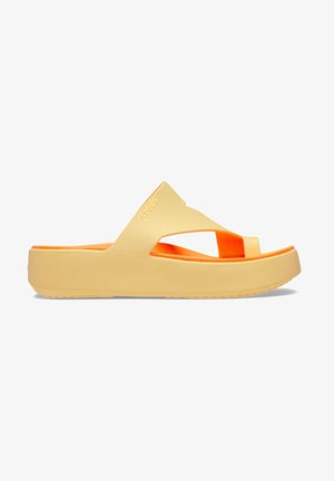 Yellow platform slide sandals with orange accents; made of soft material featuring crossover straps and a textured sole for grip.