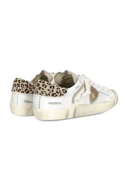 Zapatillas blancas de corte bajo con detalles beige, lengüetas con estampado de leopardo en el talón y suelas de goma beige, mostradas desde una vista lateral trasera.