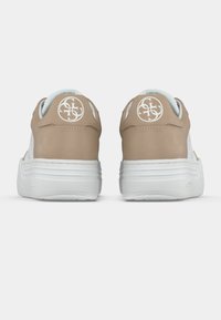 Sneakers in pelle beige con suola bianca, caratterizzate da un logo circolare sul tallone e dettagli traforati per una migliore traspirabilità.
